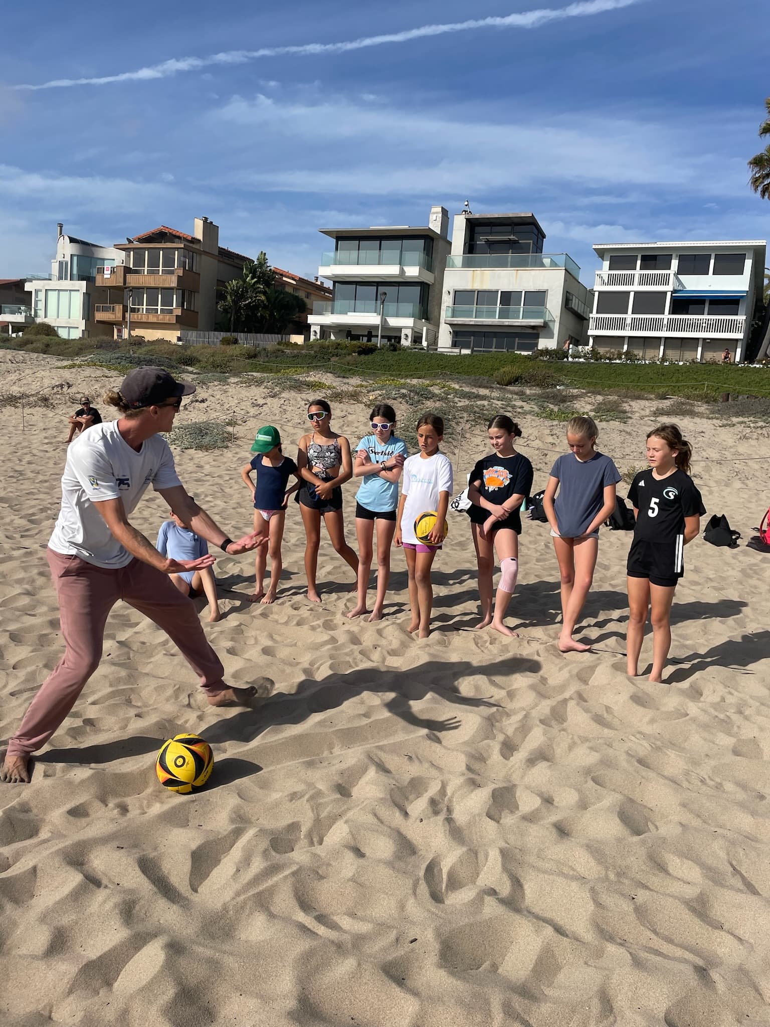 John Schwengel coaching junior beach volleyball players on the sand