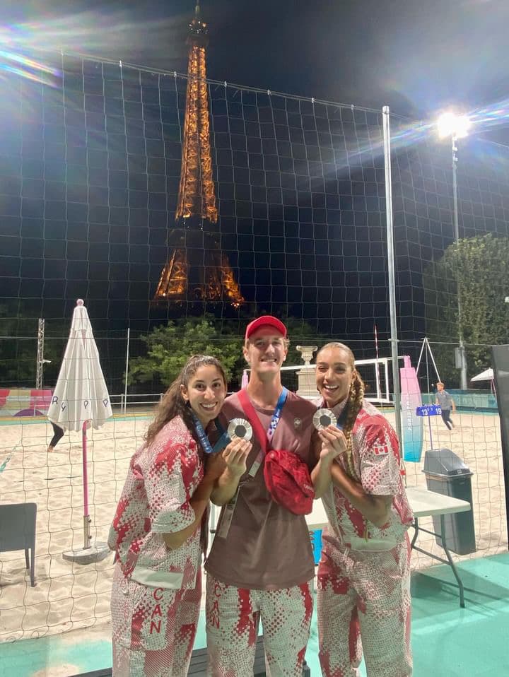 John Schwengel with Brandie Wilkerson and Melissa Humana-Paredes holding their Olympic silver medals beneath the Eiffel Tower